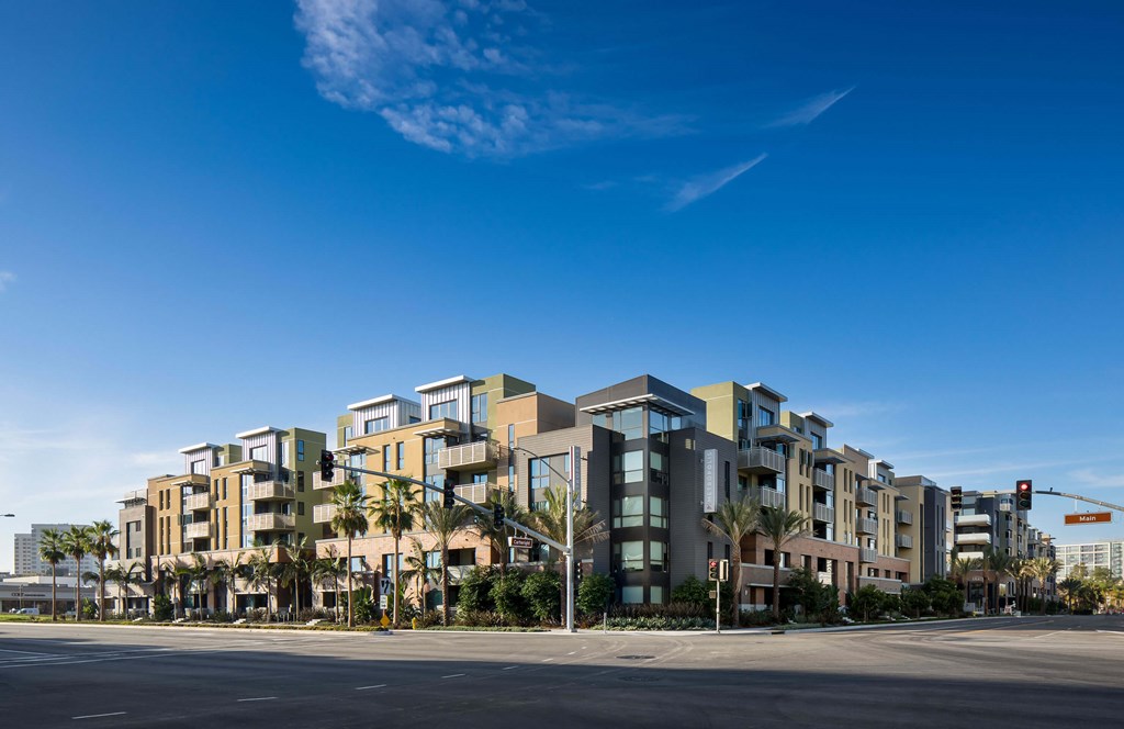 A row of modern buildings with palm trees in front.