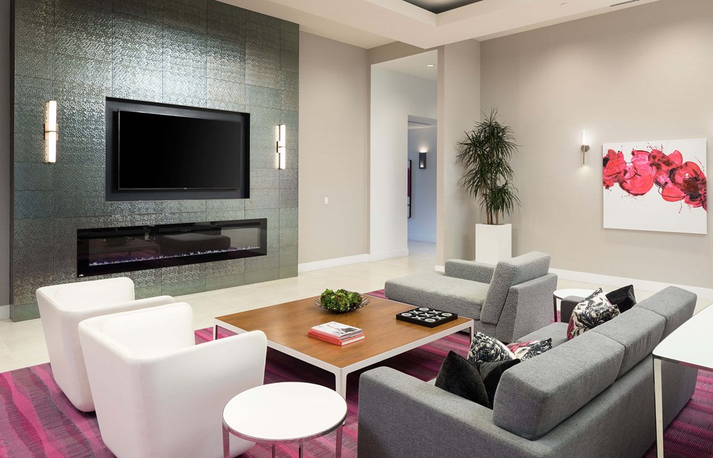 A modern living room with a grey couch, a white chair, a coffee table, and a television.