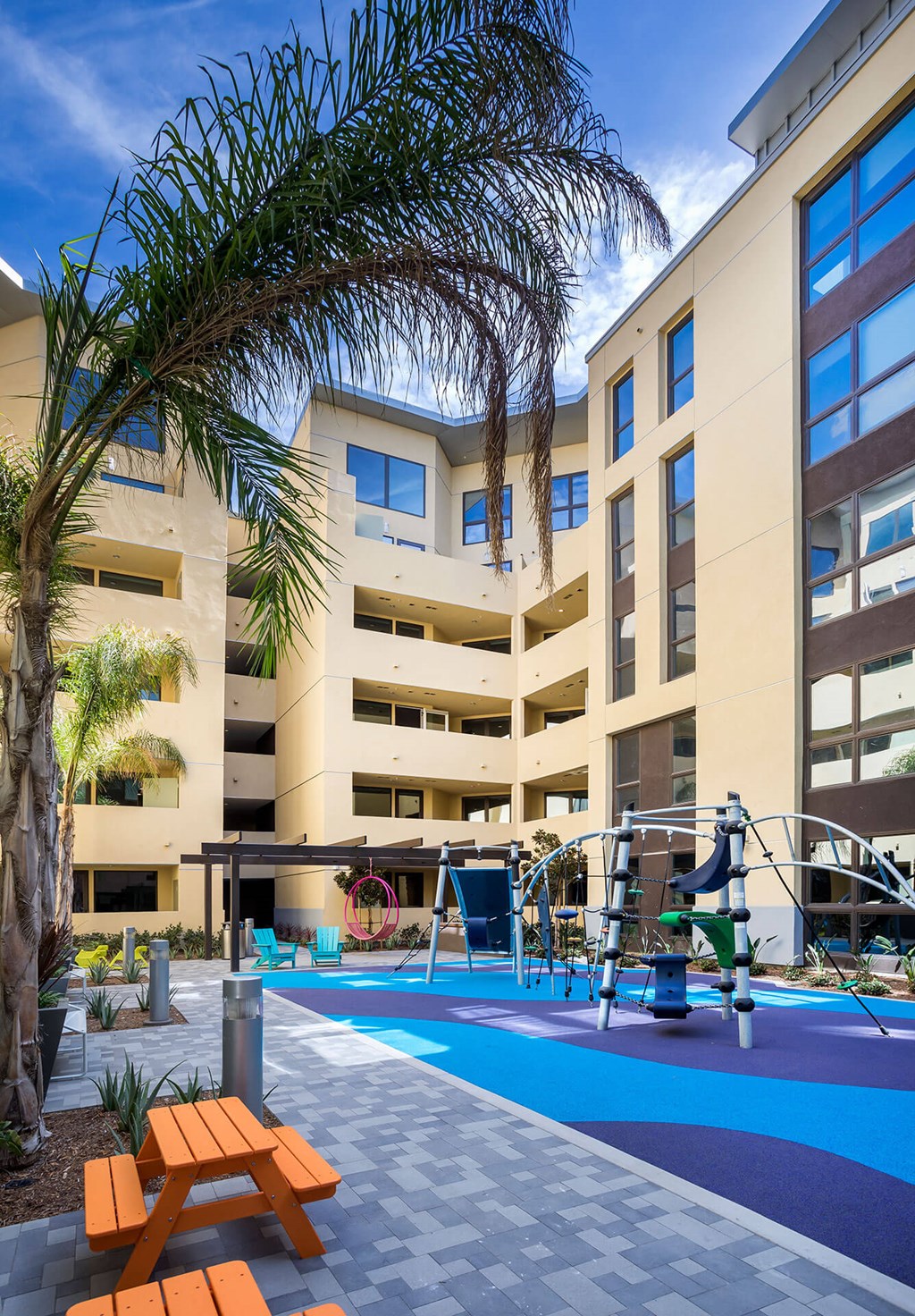 A swimming pool area with a bench and a tree in front of a building.