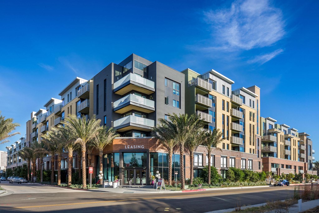 A modern multi-story building with a leasing office in front.