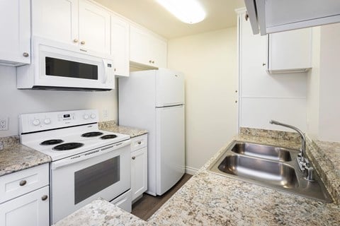 A kitchen with white appliances and granite countertops.