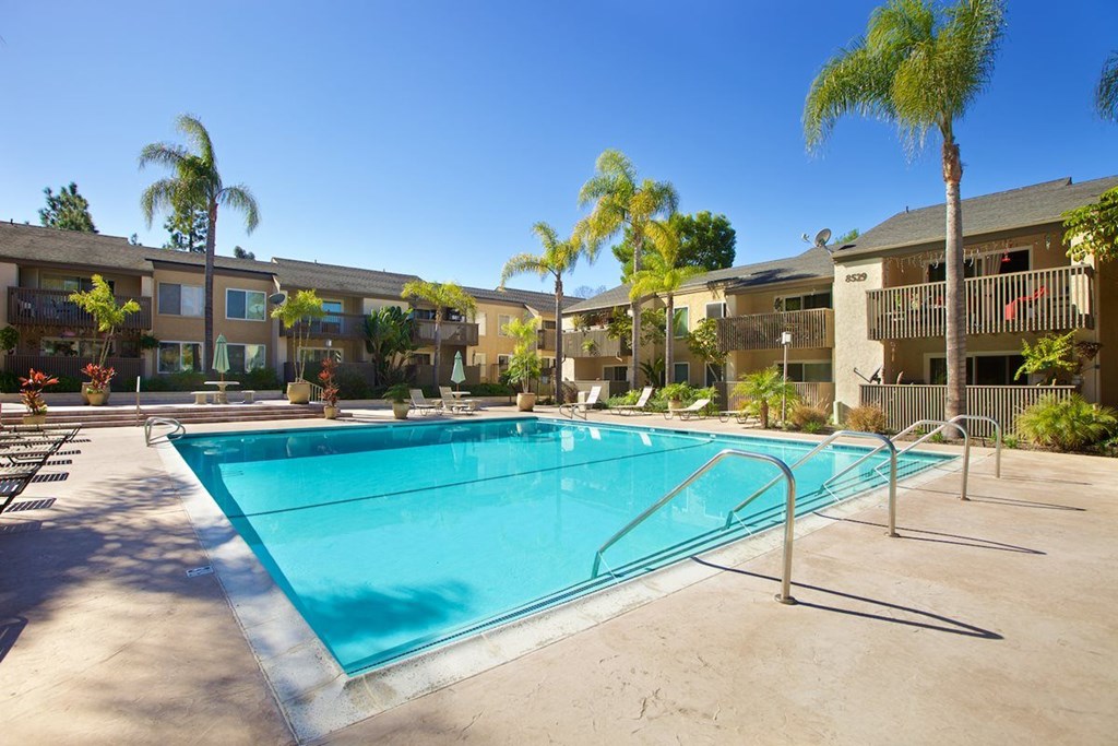 A swimming pool surrounded by palm trees and apartment buildings.