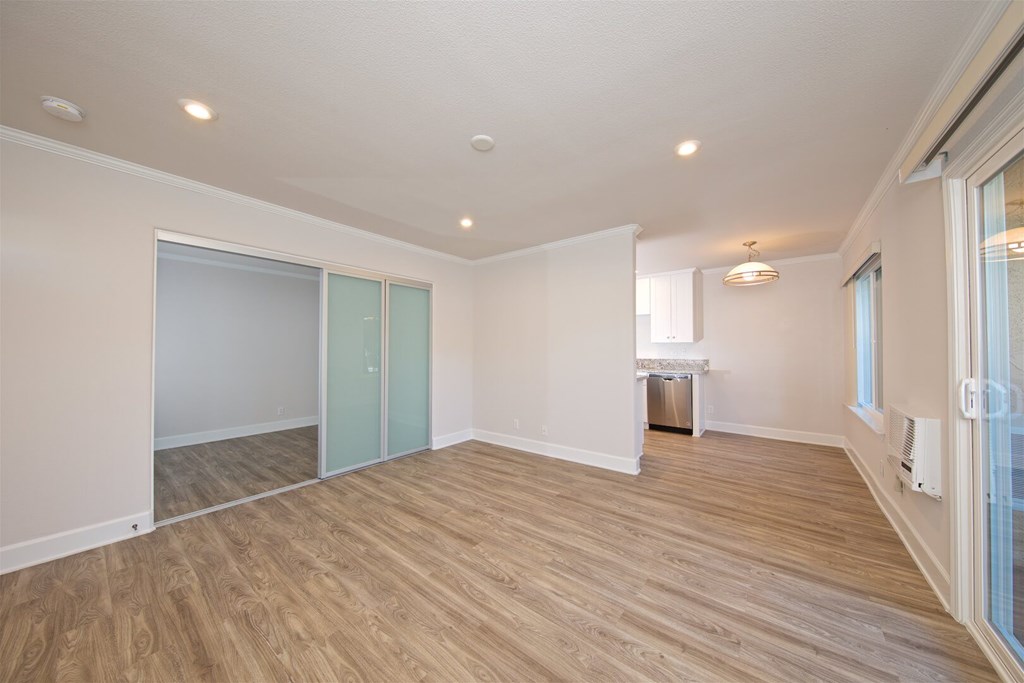 A room with wooden flooring and a window on the right side.