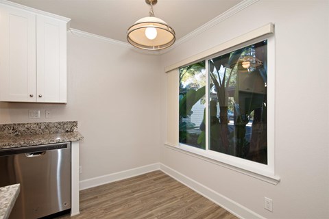 A kitchen with a stainless steel dishwasher and white cabinets.