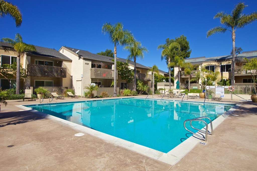 A swimming pool surrounded by palm trees and apartment buildings.