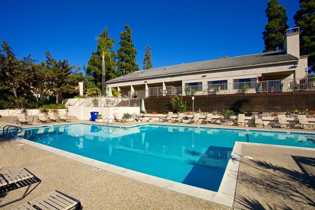 A swimming pool in front of a house with a blue sky.