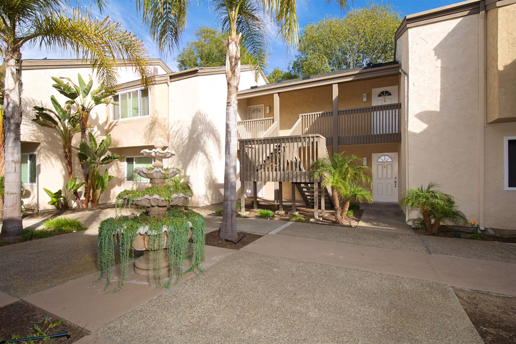 A courtyard with a fountain and a building in the background.