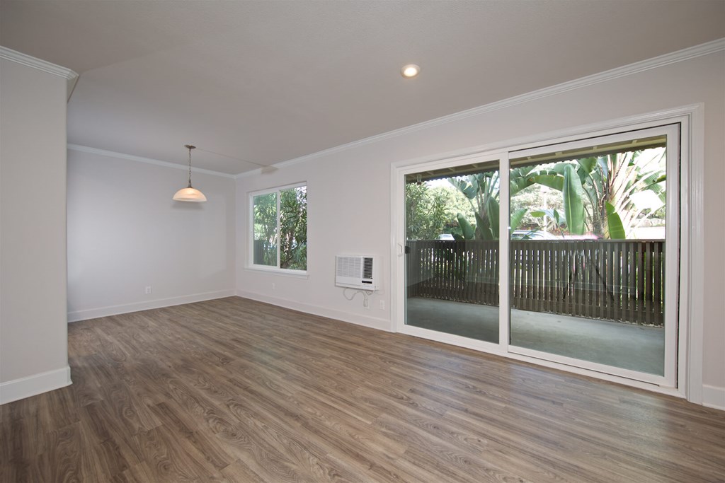 A room with a sliding glass door and wooden flooring.