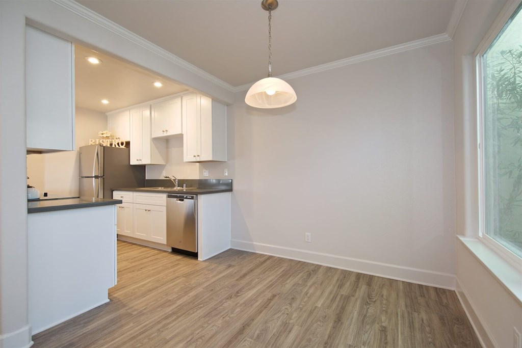 A kitchen with white cabinets and a wooden floor.
