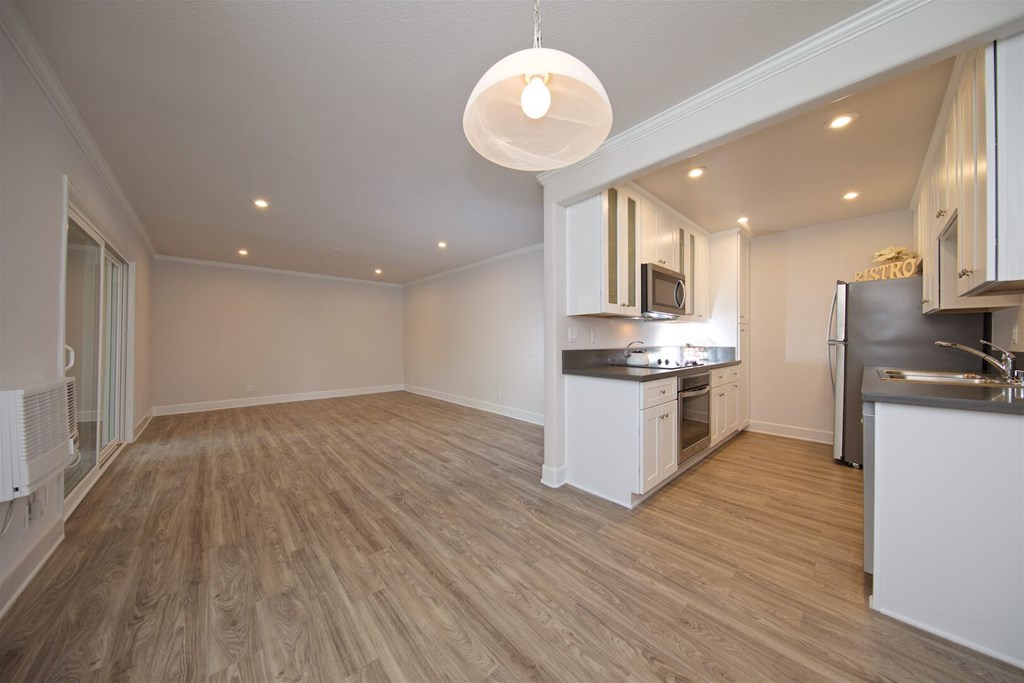 A kitchen with a wooden floor and white cabinets.