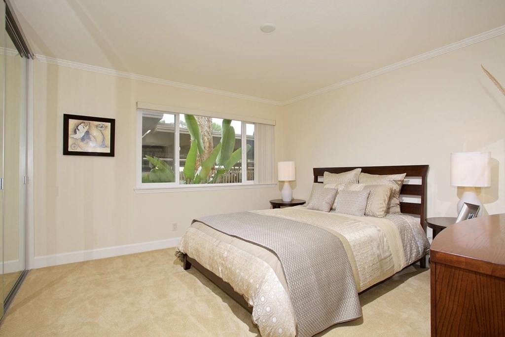 A bedroom with a large bed and a picture on the wall.