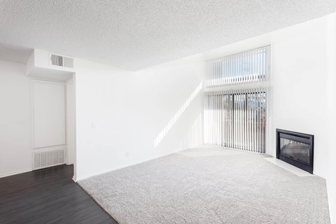 A white bedroom with a fireplace and a window with blinds.