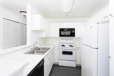 A white kitchen with a black microwave and oven.