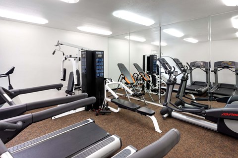 A gym with a variety of equipment including treadmills, weights, and exercise machines.