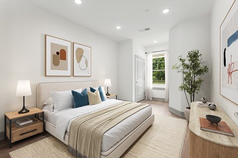 A bedroom with a large bed, a nightstand with a lamp, and two framed pictures on the wall.
