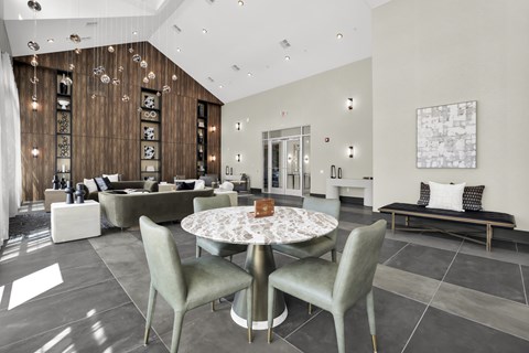 A modern club room with a round table and grey chairs.