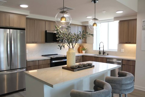 A modern kitchen with a large island and grey chairs.