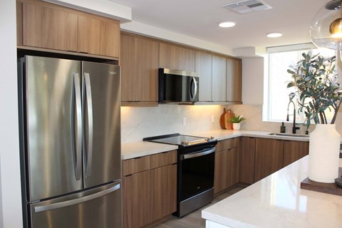 A modern kitchen with a stainless steel refrigerator and wooden cabinets.