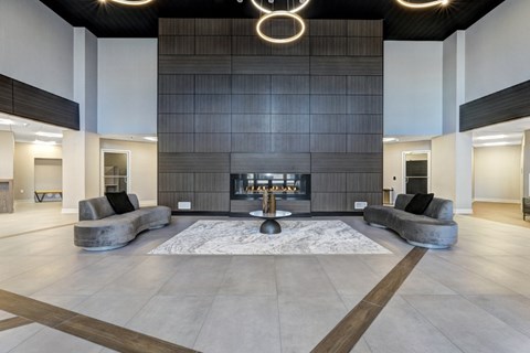 A modern lobby with a fireplace and a large rug.