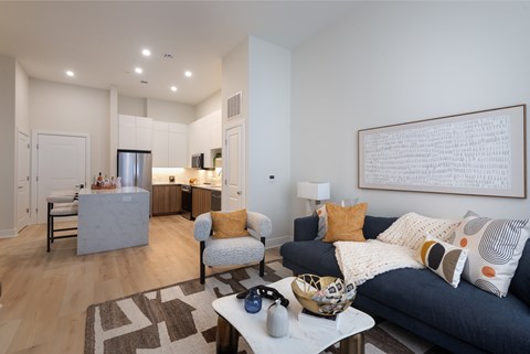 A modern living room with a grey couch and a large abstract painting on the wall.