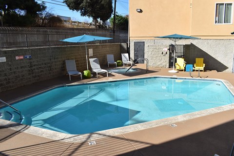A small pool with a blue umbrella and chairs.