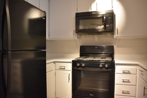 A black stove and oven in a kitchen with white cabinets.