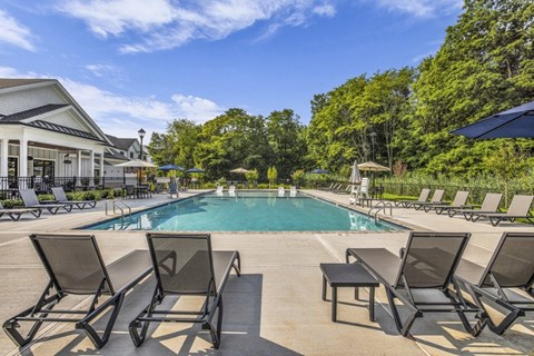 A pool surrounded by lounge chairs and trees.