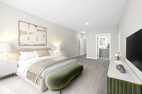 A bedroom with a large bed and a green footstool.
