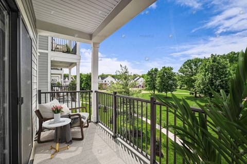 A balcony with a table and chairs overlooking a green lawn.