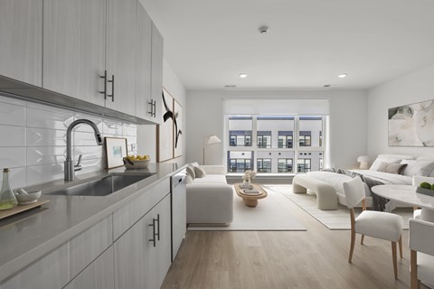 A modern kitchen with white cabinets and a large window.