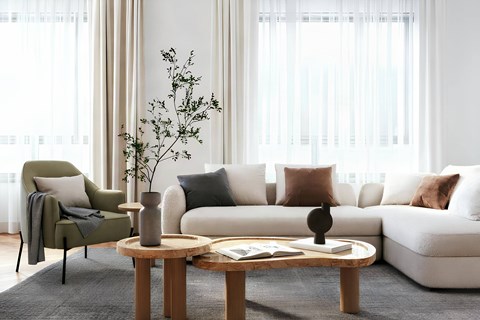 A living room with a white couch, a green chair, and a wooden coffee table.