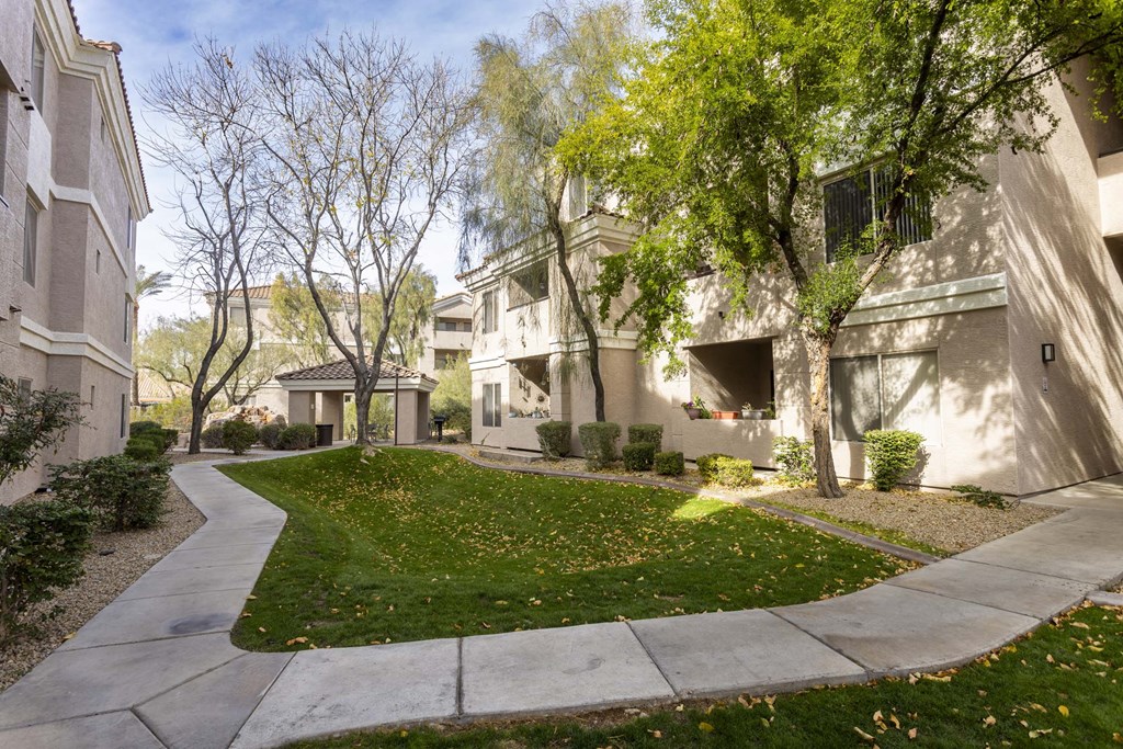 A pathway leads through a grassy area between two apartment buildings.at Vintage at Scottsdale, SCOTTSDALE, AZ