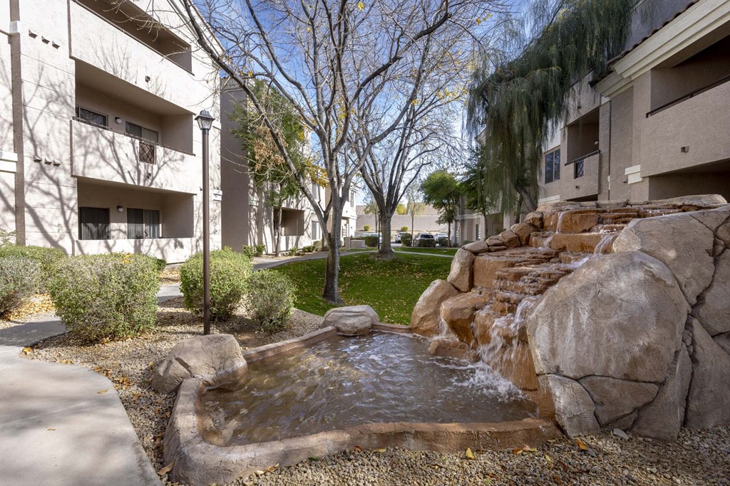 A small waterfall in a courtyard surrounded by rocks.at Vintage at Scottsdale, SCOTTSDALE, AZ