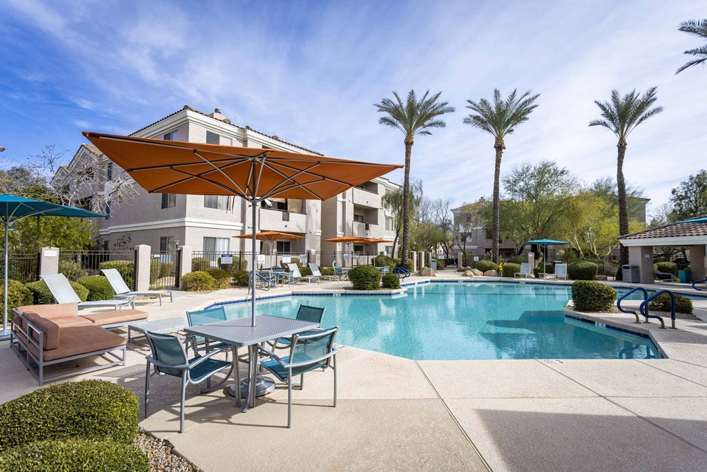 A pool area with a table and chairs and a sun shade.at Vintage at Scottsdale, Arizona