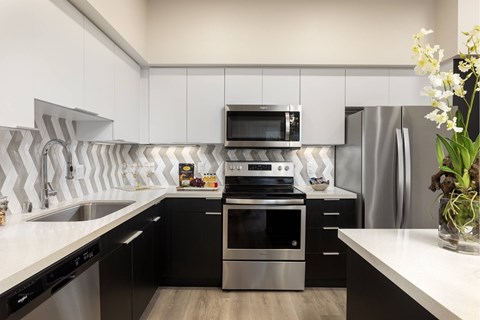 A modern kitchen with black cabinets and stainless steel appliances.