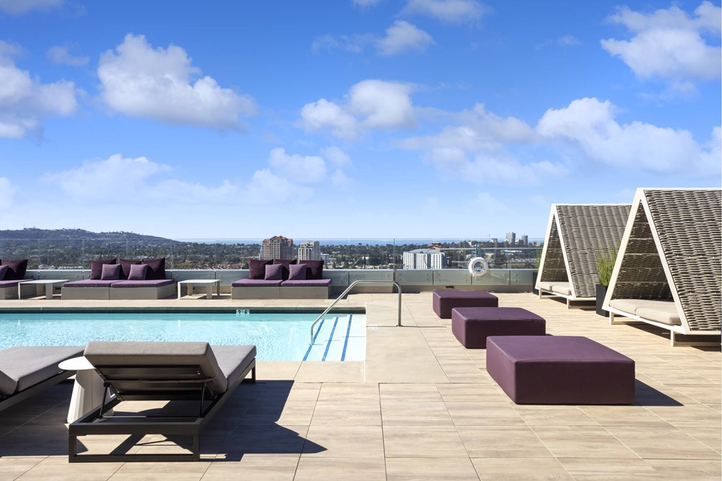 A poolside area with sun loungers and a view of the city. at LUX by Garden*, San Diego, California