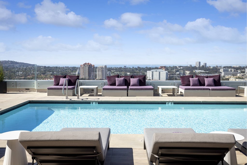 A pool with lounge chairs and a city view in the background. at LUX by Garden*, San Diego, California