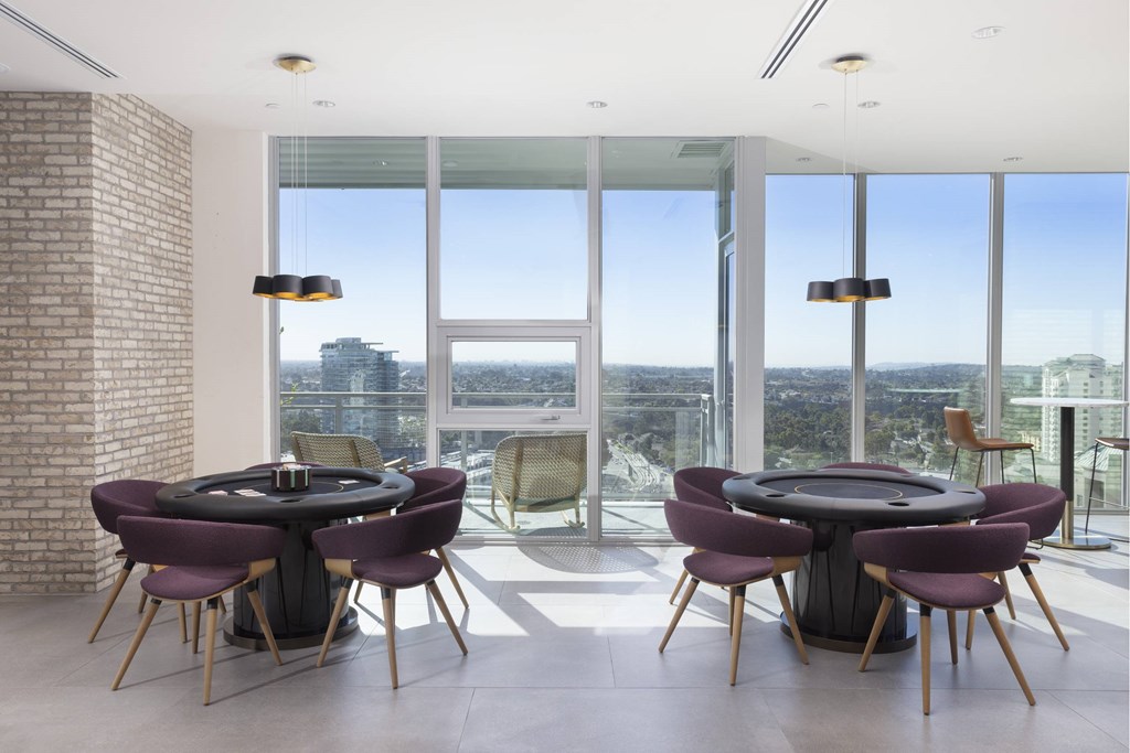 A black table surrounded by chairs in a room with a brick wall and a view of the city. at LUX by Garden*, California, 92122