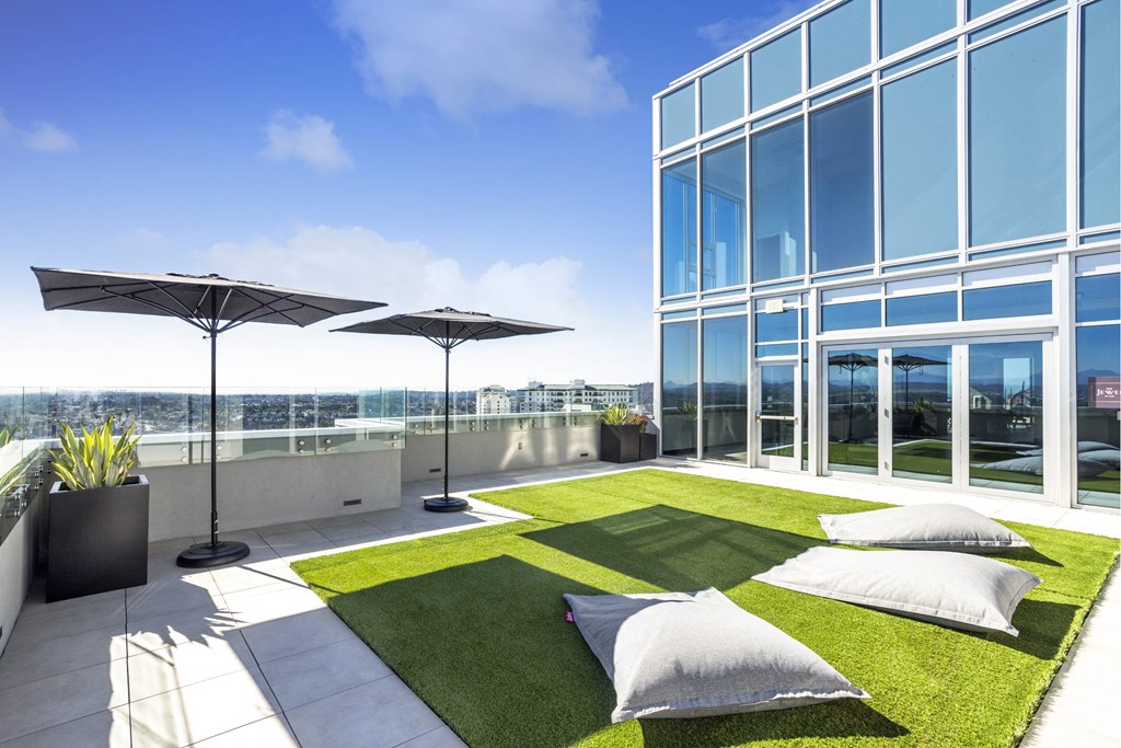 A modern outdoor patio area with a grassy lawn and two umbrellas. at LUX by Garden*, California, 92122