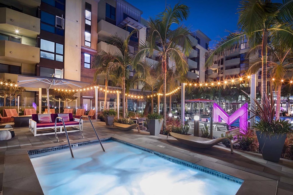 A pool area with a hot tub and lounge chairs.