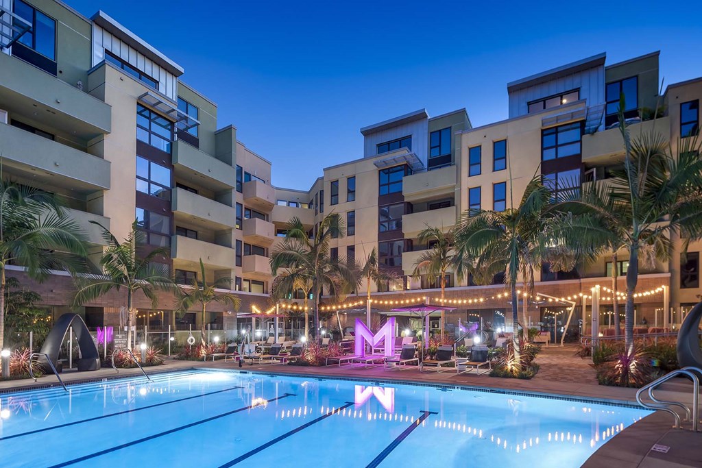 A swimming pool in front of apartment buildings at dusk.