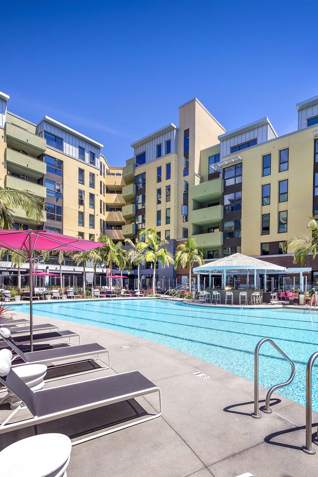 A pool area with sun loungers and a building in the background.