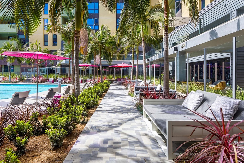 A poolside area with a bench, plants, and umbrellas.