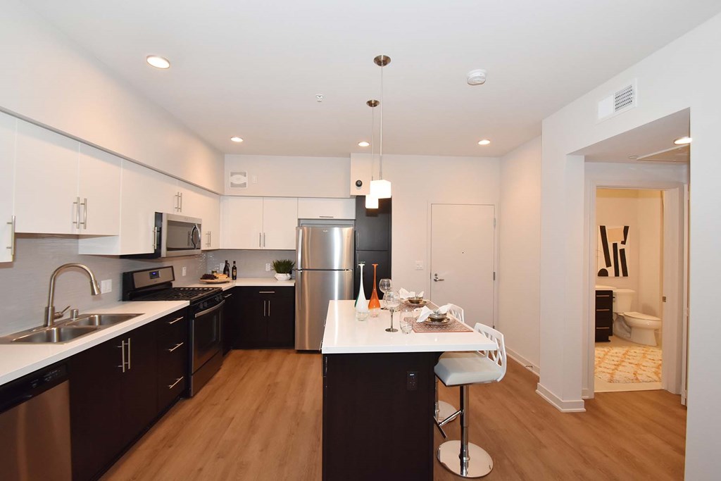 A modern kitchen with dark wood floors and white countertops.