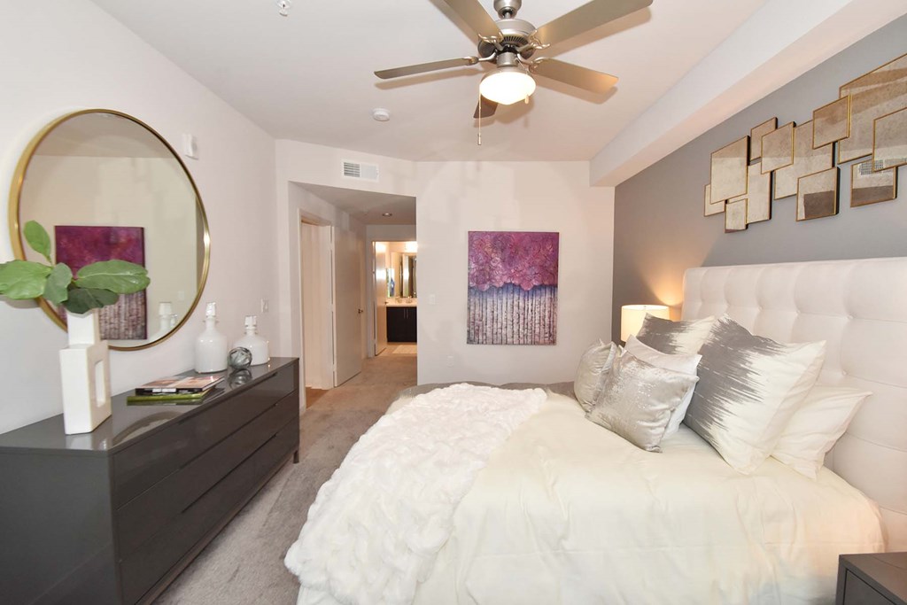 A bedroom with a large bed and a ceiling fan.