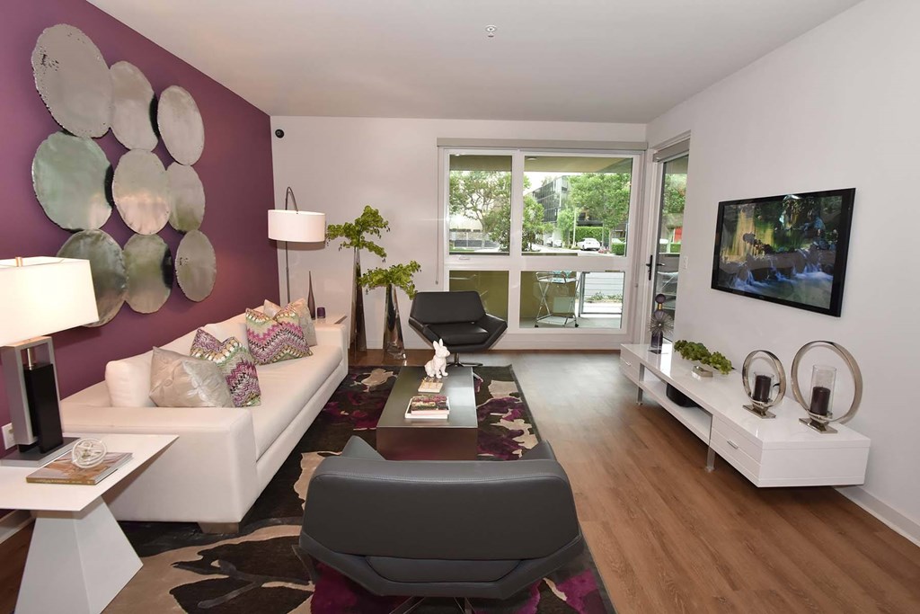 A modern living room with a white sofa, a grey armchair, and a wooden coffee table.