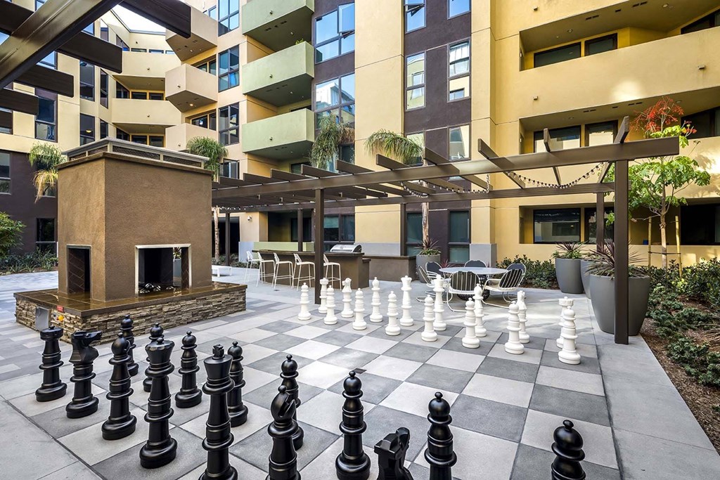 A chess board with black and white pieces in front of a building.