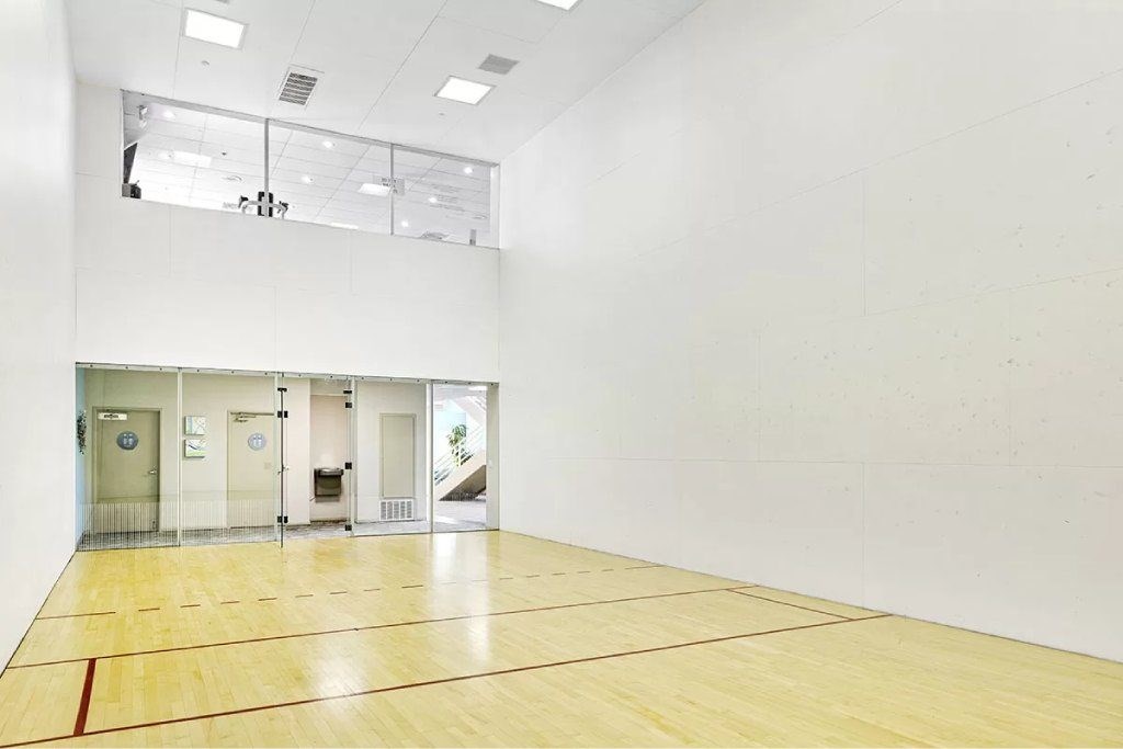 A squash court with a wooden floor and white walls.