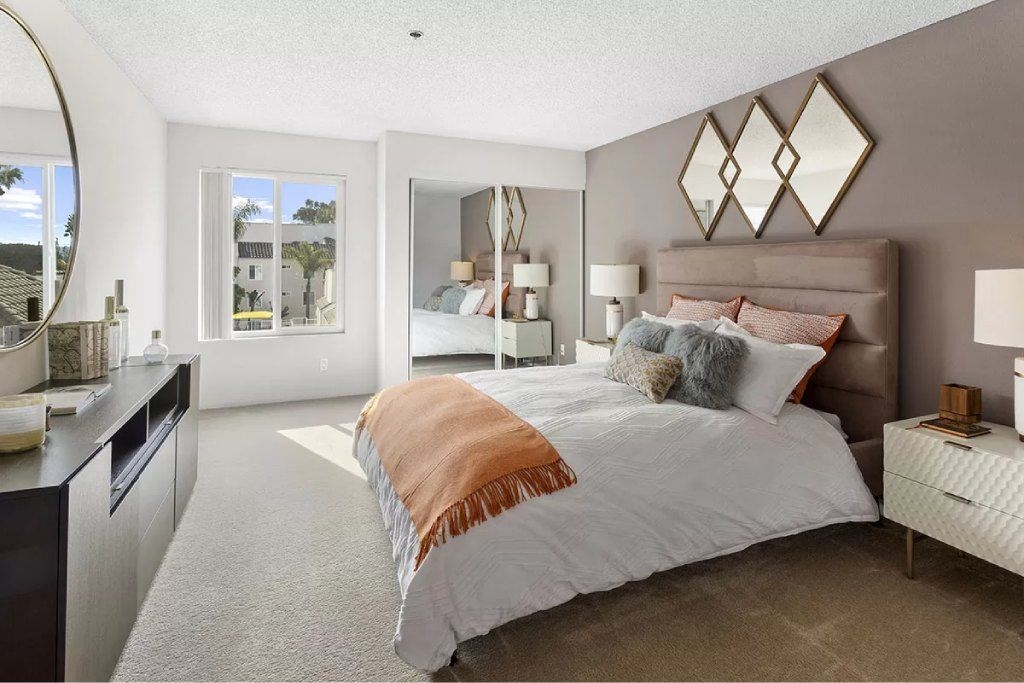 A bedroom with a large bed and a mirror on the wall.