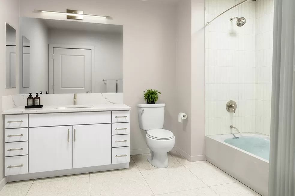 A white bathroom with a toilet, sink, and bathtub.at Volar Apartments, California